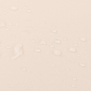 Detailaufnahme: Beige Kissenbezug mit Wassertropfen der Gartenmöbel-Garnitur.
