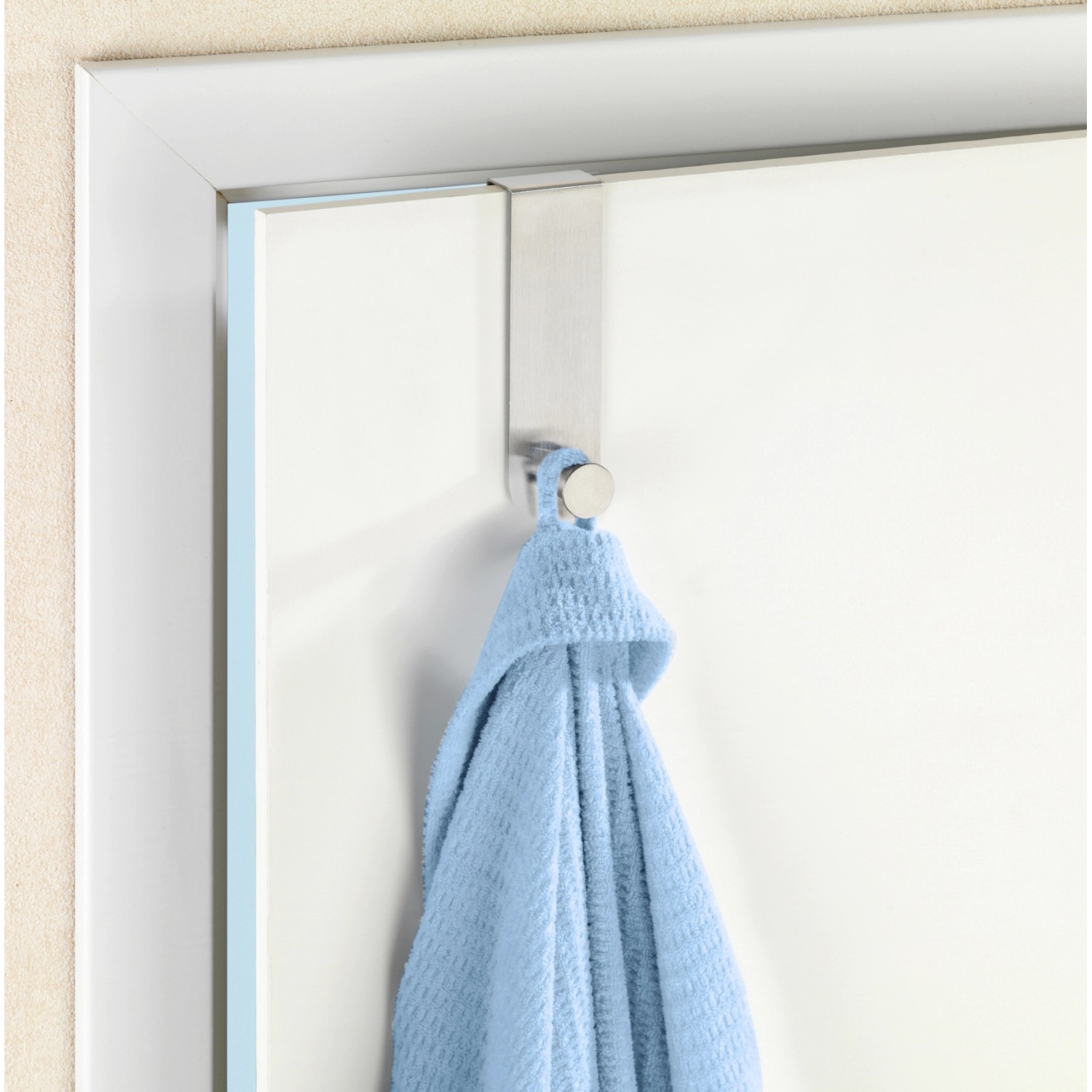 Wenko Türhaken Celano aus Edelstahl mit blauem Handtuch an weißer Tür.