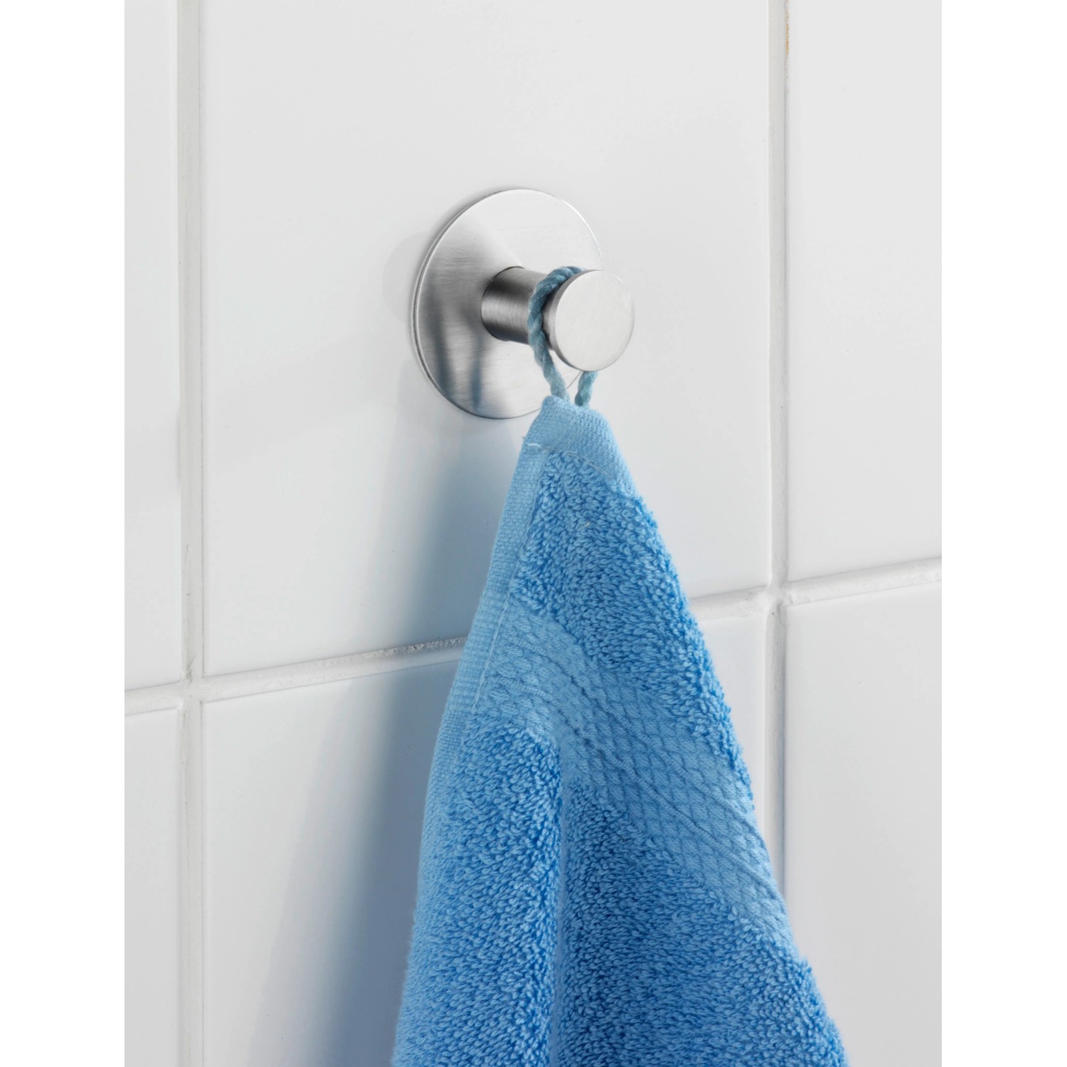 Wenko Wandhaken Celano aus Edelstahl mit blauem Handtuch an weißer Wand.