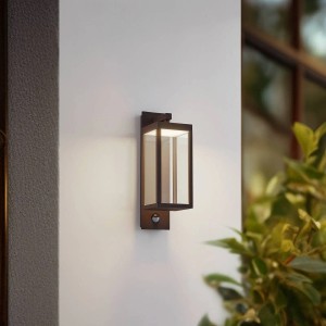 Moderne, braune Lucande LED Außenwandleuchte Ferdinand mit Bewegungsmelder an weißer Hauswand.