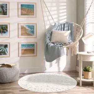 Runder, pastell-cremefarbener Hochflor-Teppich Nara mit Boho-Rautenmuster im Wohnzimmer.