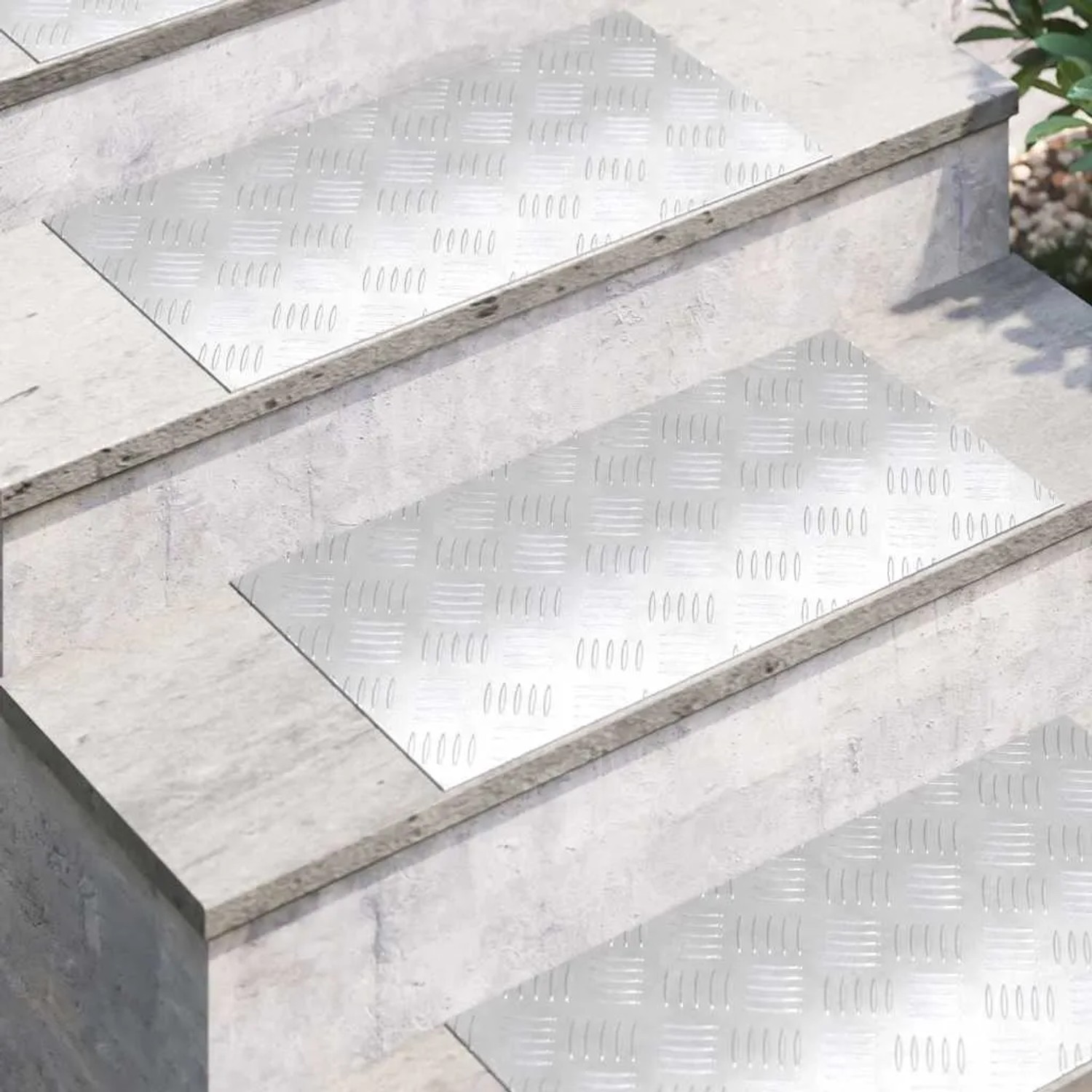 Silberne Aluminium Rautenscheiben mit Riffelblechmuster auf Betontreppen. Rutschfeste Stufenmatten für Innen- & Außenbereich.