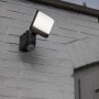 Lutec Solar LED-Strahler Sunshine mit Solarpanel an grauer Backsteinwand.