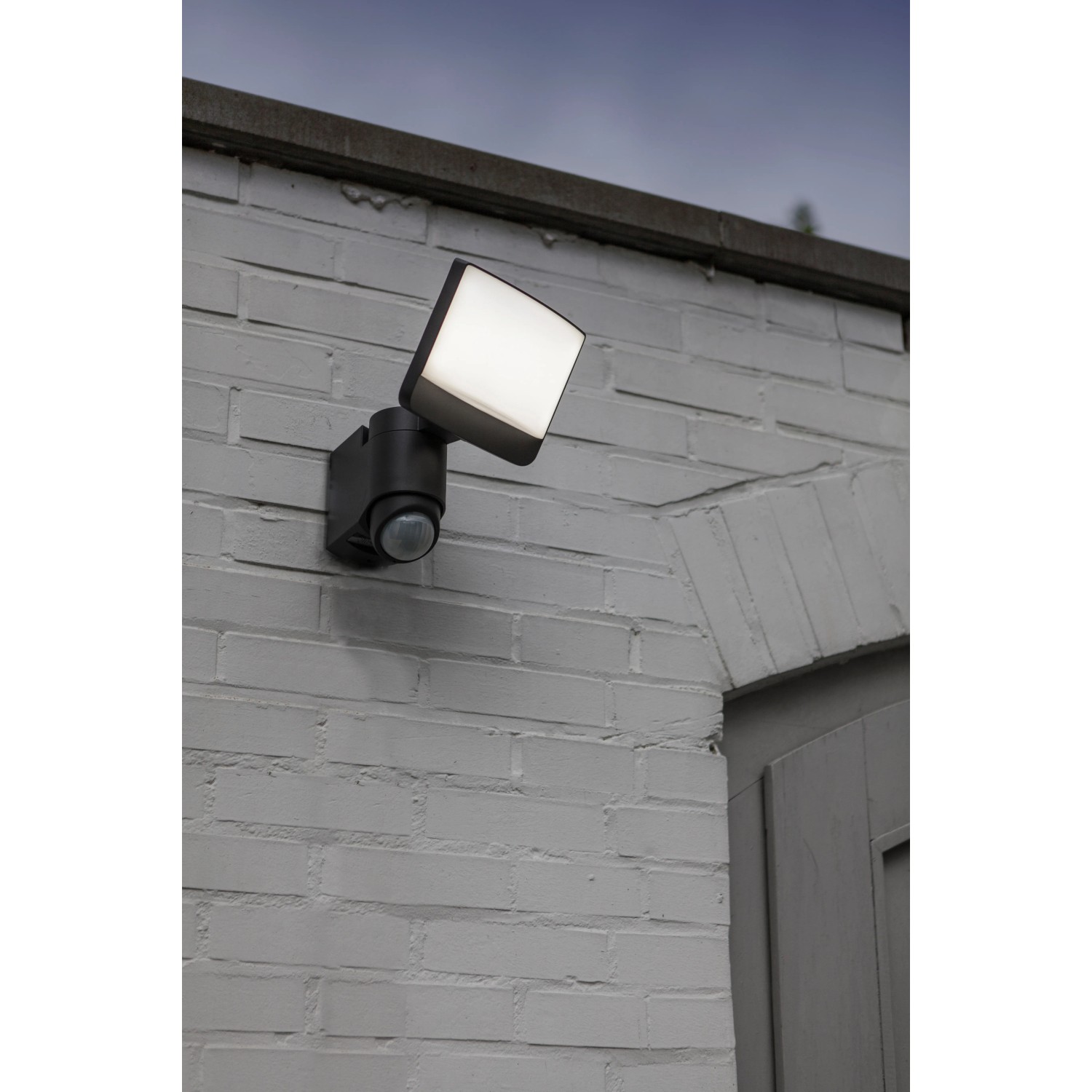Lutec Solar LED-Strahler Sunshine mit Solarpanel an grauer Backsteinwand.