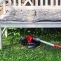 Einhell Akku-Rasentrimmer GE-CT 18/30 Li-Solo unter einer Gartenbank auf Rasen.