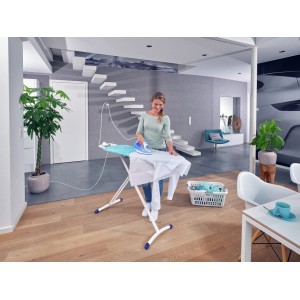 Frau bügelt Hemd auf Leifheit Bügeltisch AirBoard Premium M Plus mit Bügeleisen.