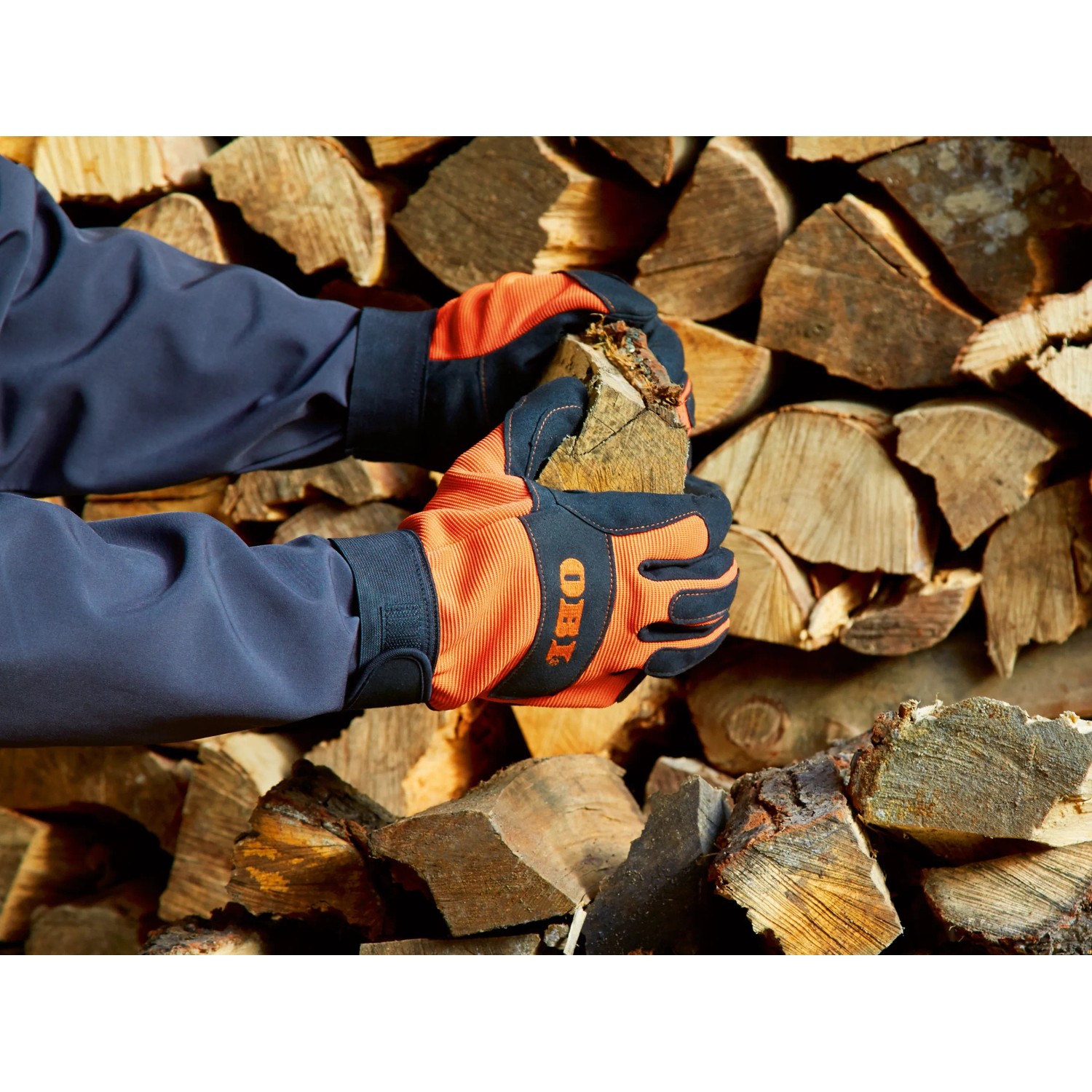 Hände mit OBI Arbeitshandschuhen (Größe 10) halten Holz vor Holzstapel. Gartenbekleidung.