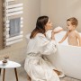 Weißer Emke Badheizkörper mit Handtuch und Mutter mit Kind in Badewanne im Badezimmer.