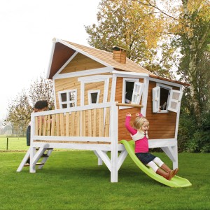 Axi Emma Spielhaus mit Rutsche: Braun-weißes Holzhaus im Garten, Kinder spielen.
