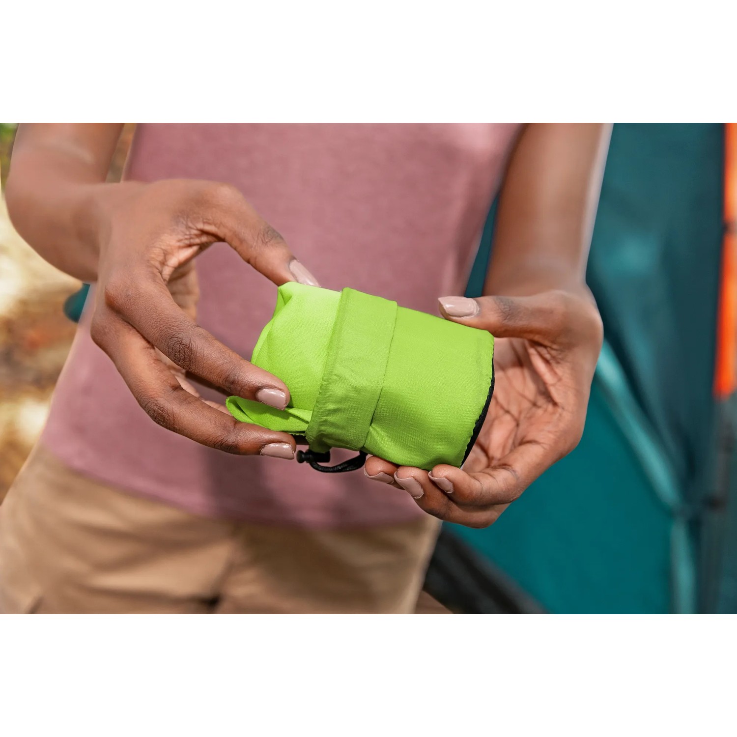 Bestway Wanderlite Luftkissen, verpackt in Grün, gehalten von Händen, Camping Zubehör.