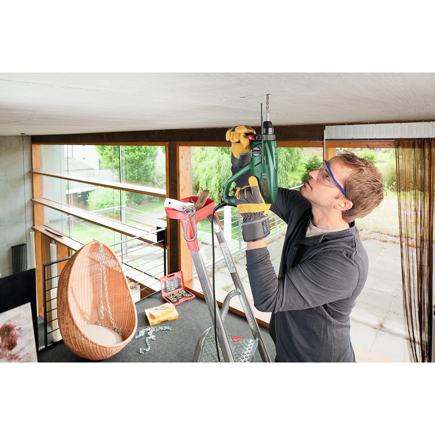 Mann bohrt mit Bosch Bohrhammer PBH 2500 SRE in Decke. Bohrmaschine für Beton.