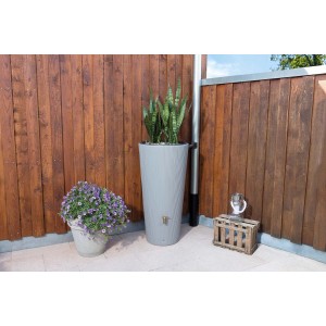 4rain VASO DECOR Regenspeicher in Zinkgrau mit Pflanzschale und Auslaufhahn vor Holzwand.