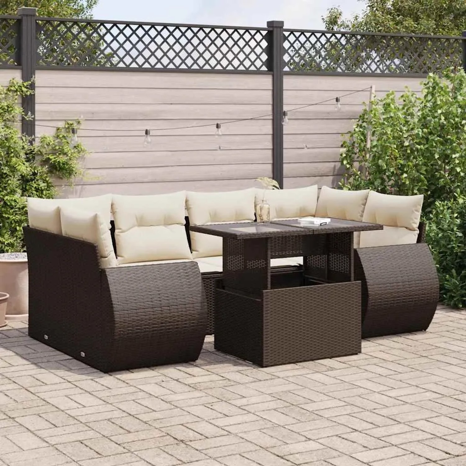 Braune 7-teilige Garten-Sofagarnitur aus Rattan mit cremefarbenen Kissen und Tisch mit Glasplatte.