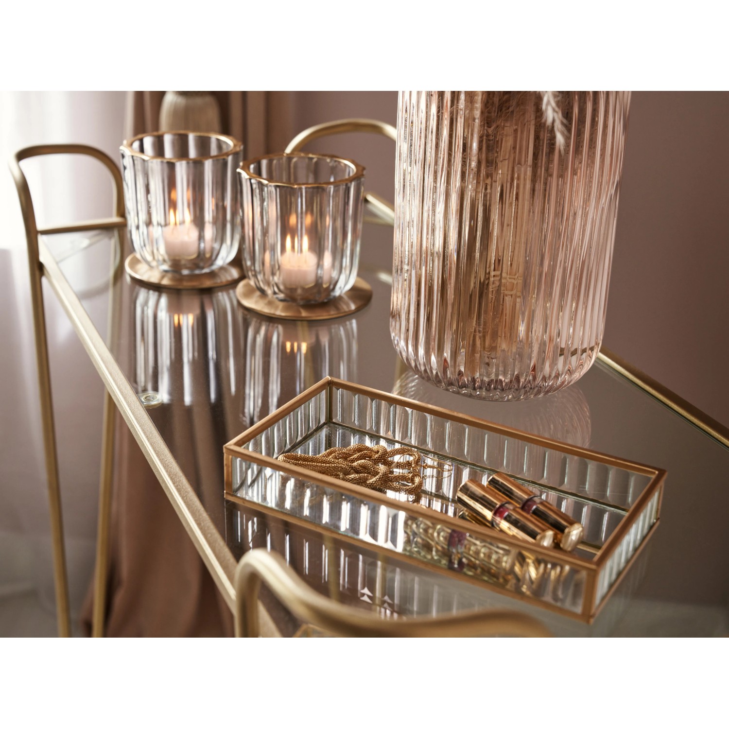 Goldfarbener Servierwagen (87,5x69,5x35cm) mit Glasablagen, dekoriert mit Kerzen, Vase und Schmuck.