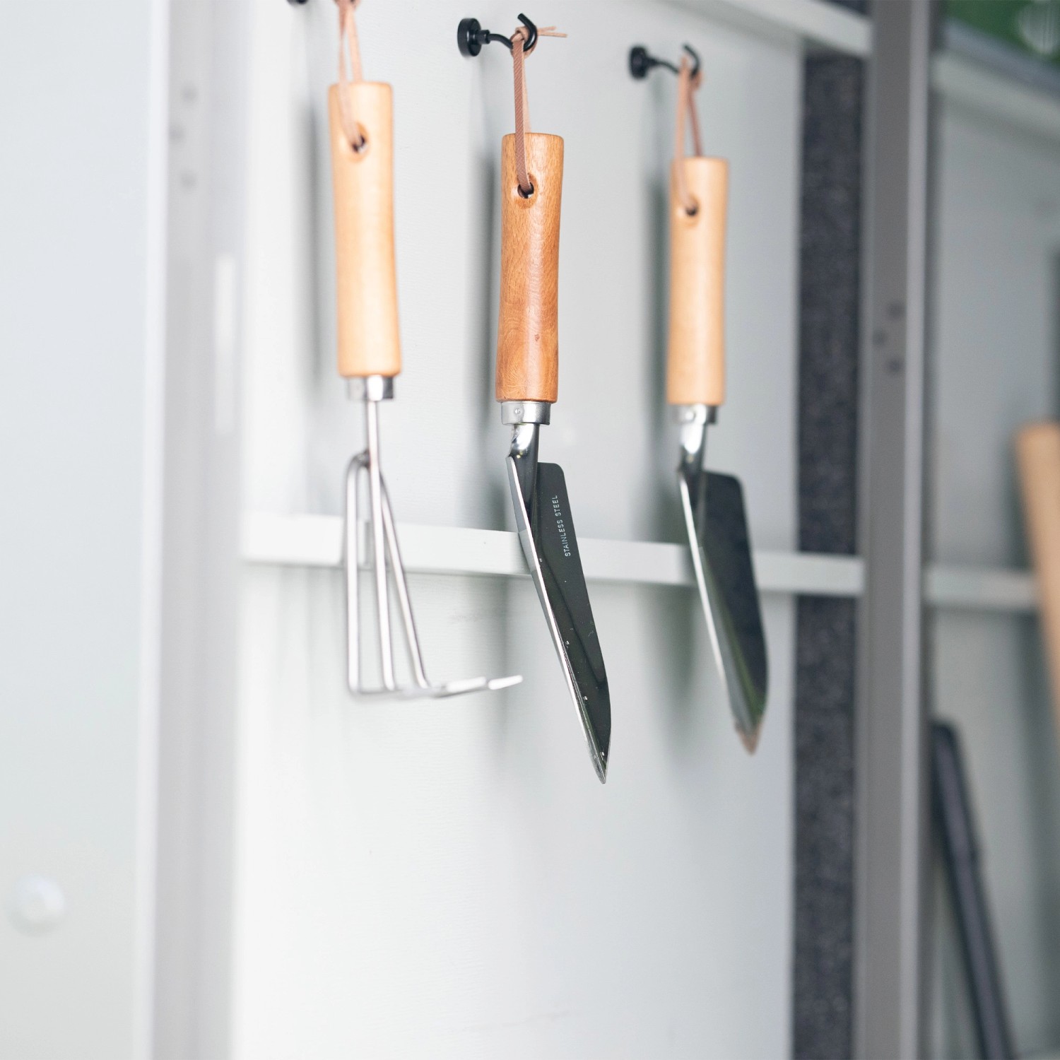 Gartengeräte hängen im Amazing Spaces Gerätehaus Shape aus Graualuminium.