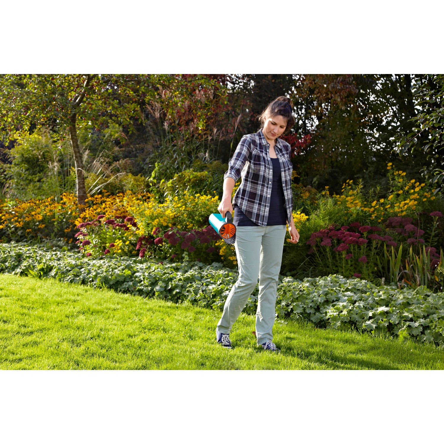 Frau nutzt Gardena Kleinstreuer S Türkis im Garten zur Düngung.
