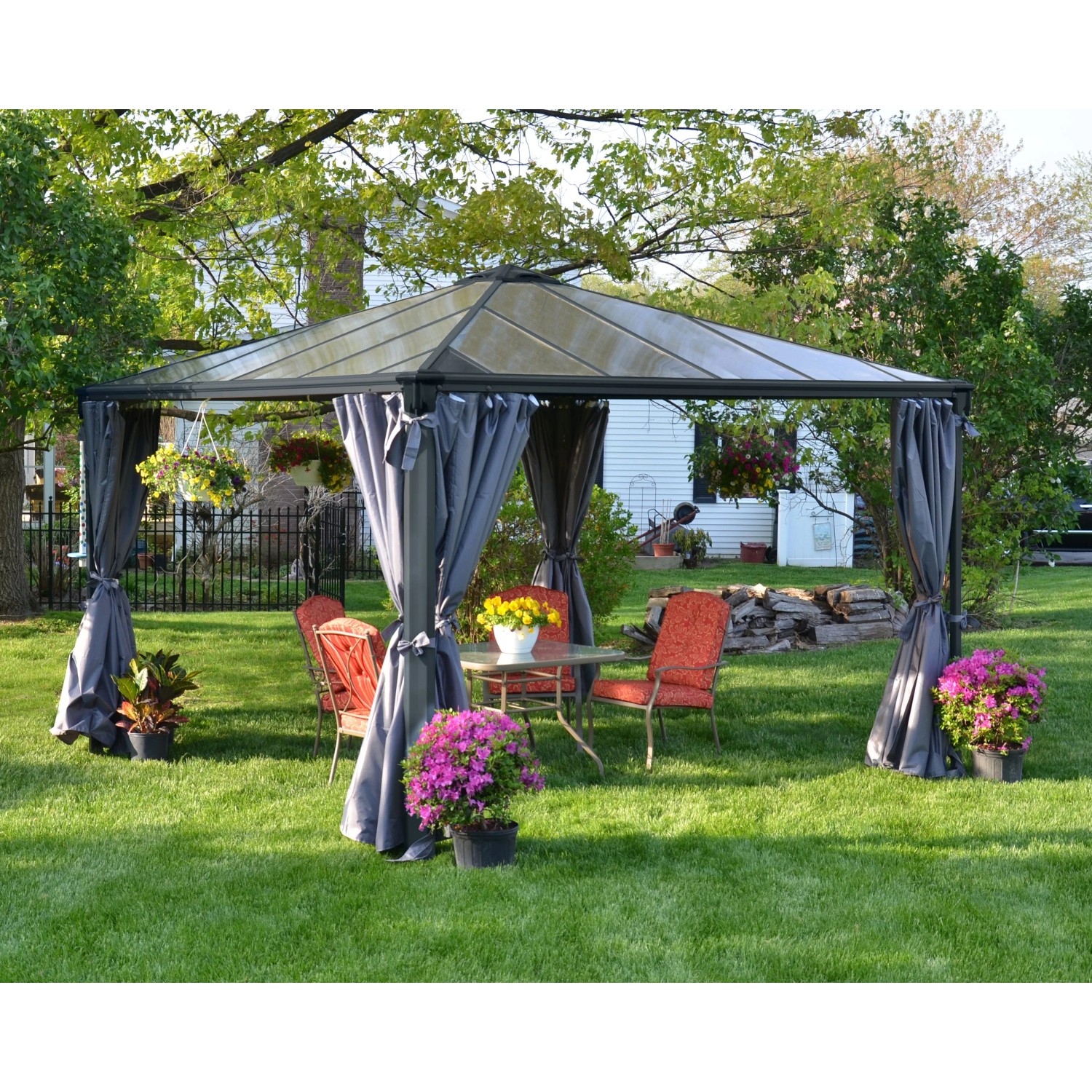 Canopia Gartenpavillon Palermo 3.6 x 3.6 Anthrazit mit Vorhängen und Gartenmöbeln im Grünen.
