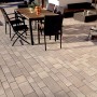 Verlegte Mehrformat-Pflastersteine Parchetto Beton Cappuccino auf Terrasse mit Gartenmöbeln.