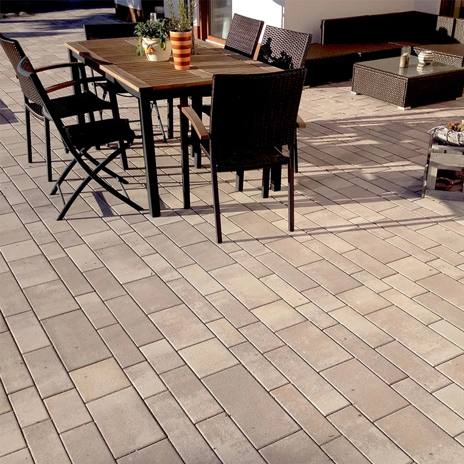 Verlegte Mehrformat-Pflastersteine Parchetto Beton Cappuccino auf Terrasse mit Gartenmöbeln.