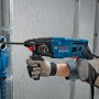 Bosch Professional GBH 2-21 Bohrhammer im Einsatz mit Staubabsaugung an einer Wand.