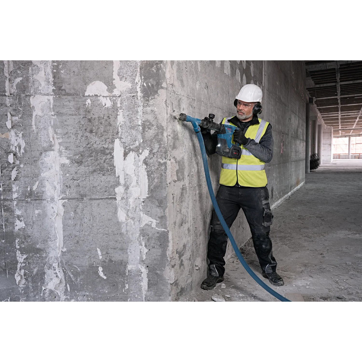 Handwerker mit Bosch Akku-Schlaghammer GSH 18V-5 beim Stemmen einer Wand.