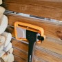 Fiskars Spalt-Axt X32 (81,5 cm) mit Klingenschutz vor Holzscheitwand.