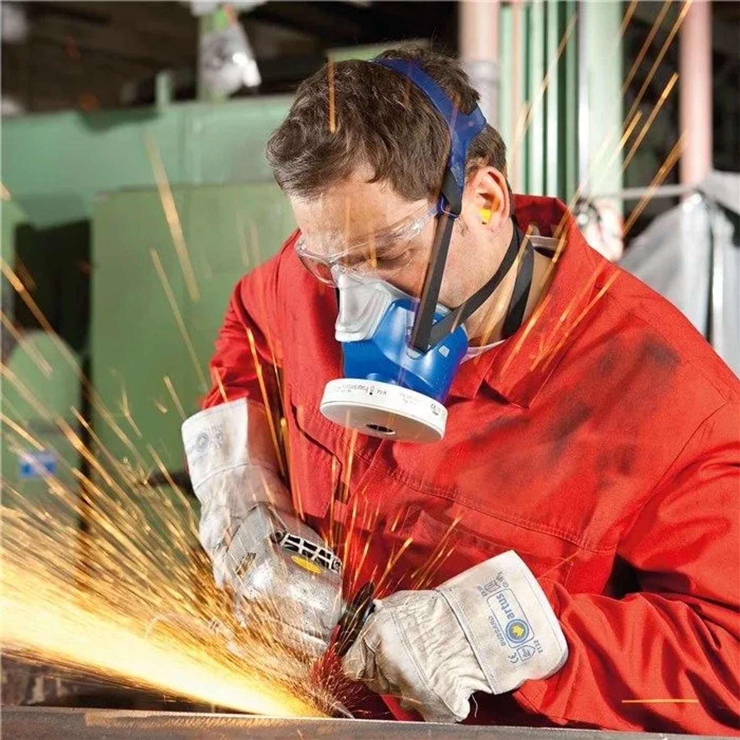 Mann mit Dräger X-plore 4740 Halbmaske, Schutzbrille und Handschuhen schleift Metall. Atemschutz für Industrie & Handwerk.
