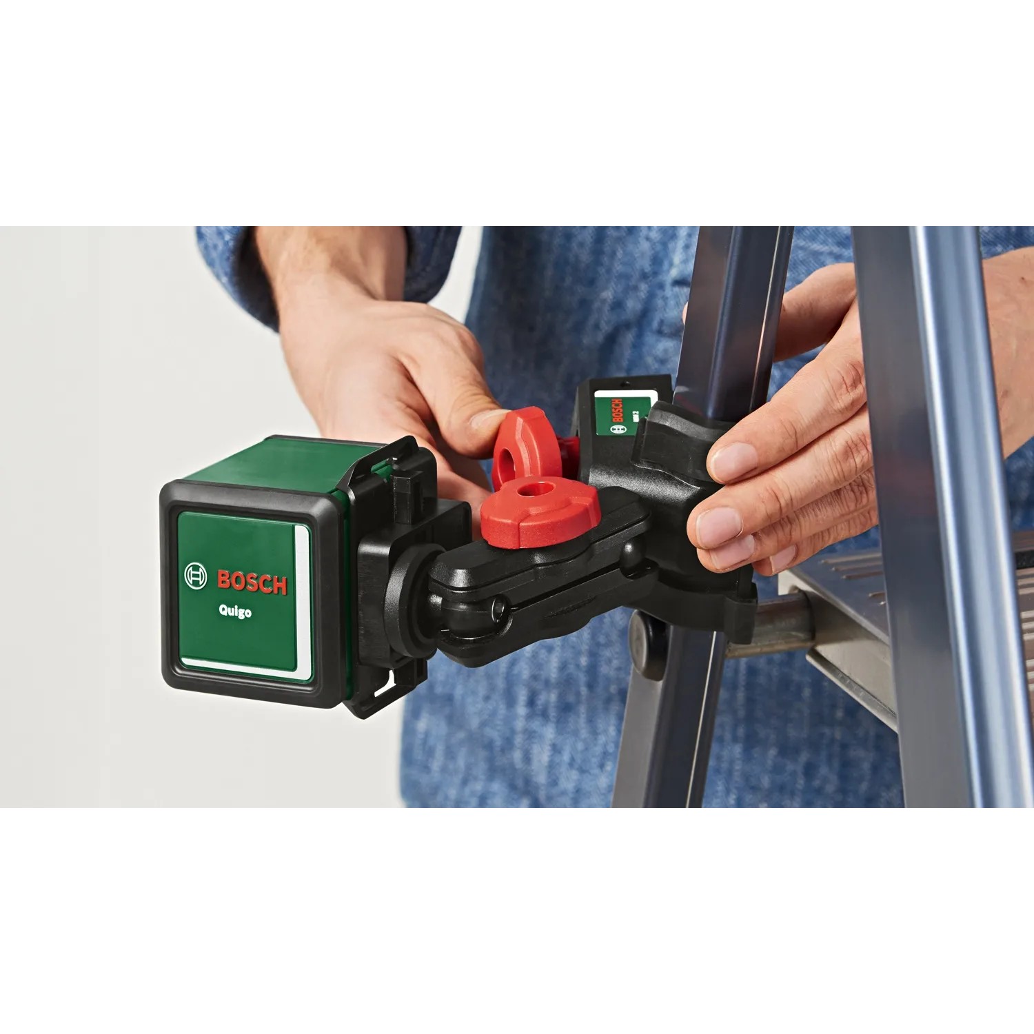 Bosch Quigo Kreuzlinienlaser mit Universalklemme MM 2 an einer Leiter befestigt.