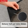 Hand zeigt rutschfeste TPE-Rückseite der beigen Floordirekt Karat Schmutzfangmatte auf Fliesenboden. Detailansicht der Struktur.