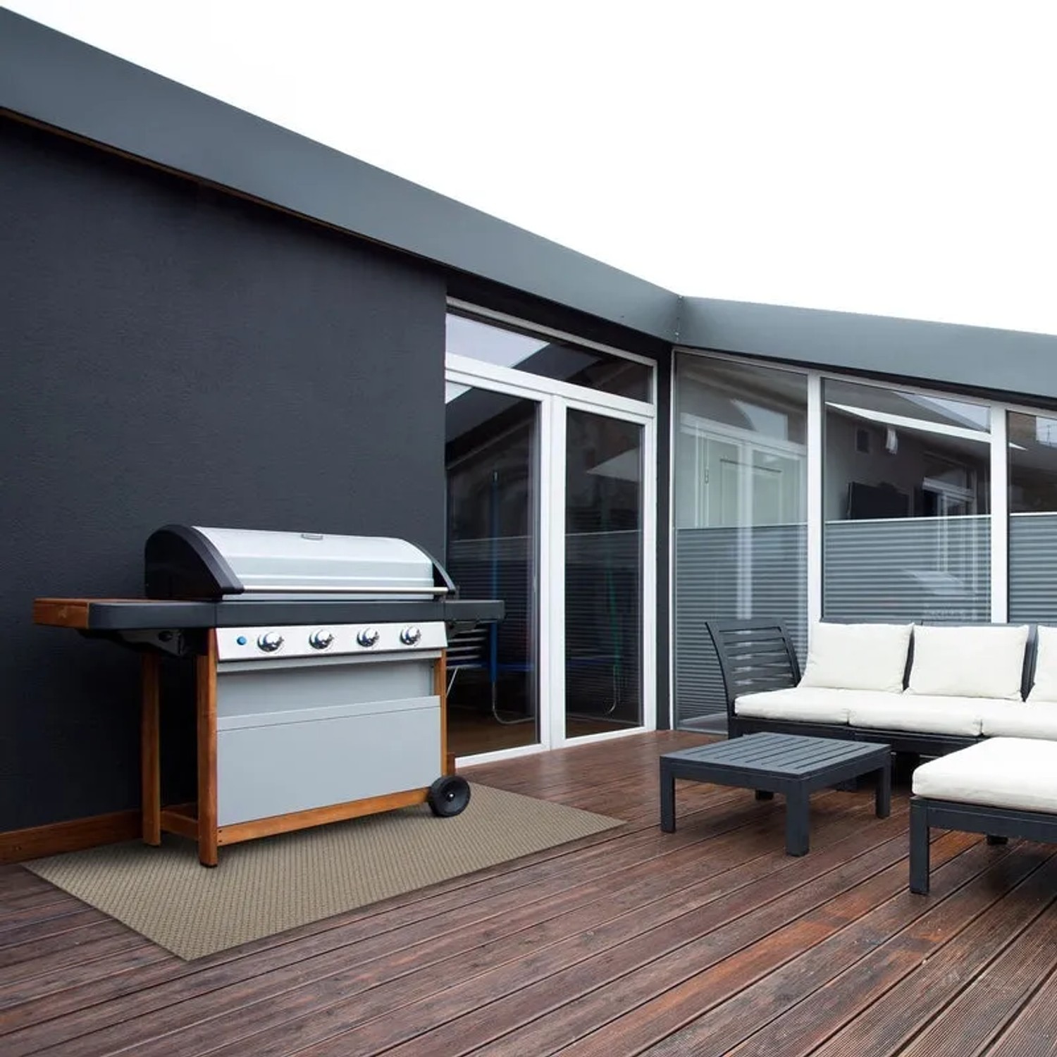 Wetterfester KARAT Outdoor Teppich Pavia, beige, 90x150 cm, auf einer Holzterrasse mit Grill und Gartenmöbeln.
