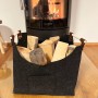 Schwarze KARAT Filztasche Vesta als Kaminholztasche mit Holzgriffen vor Kamin.
