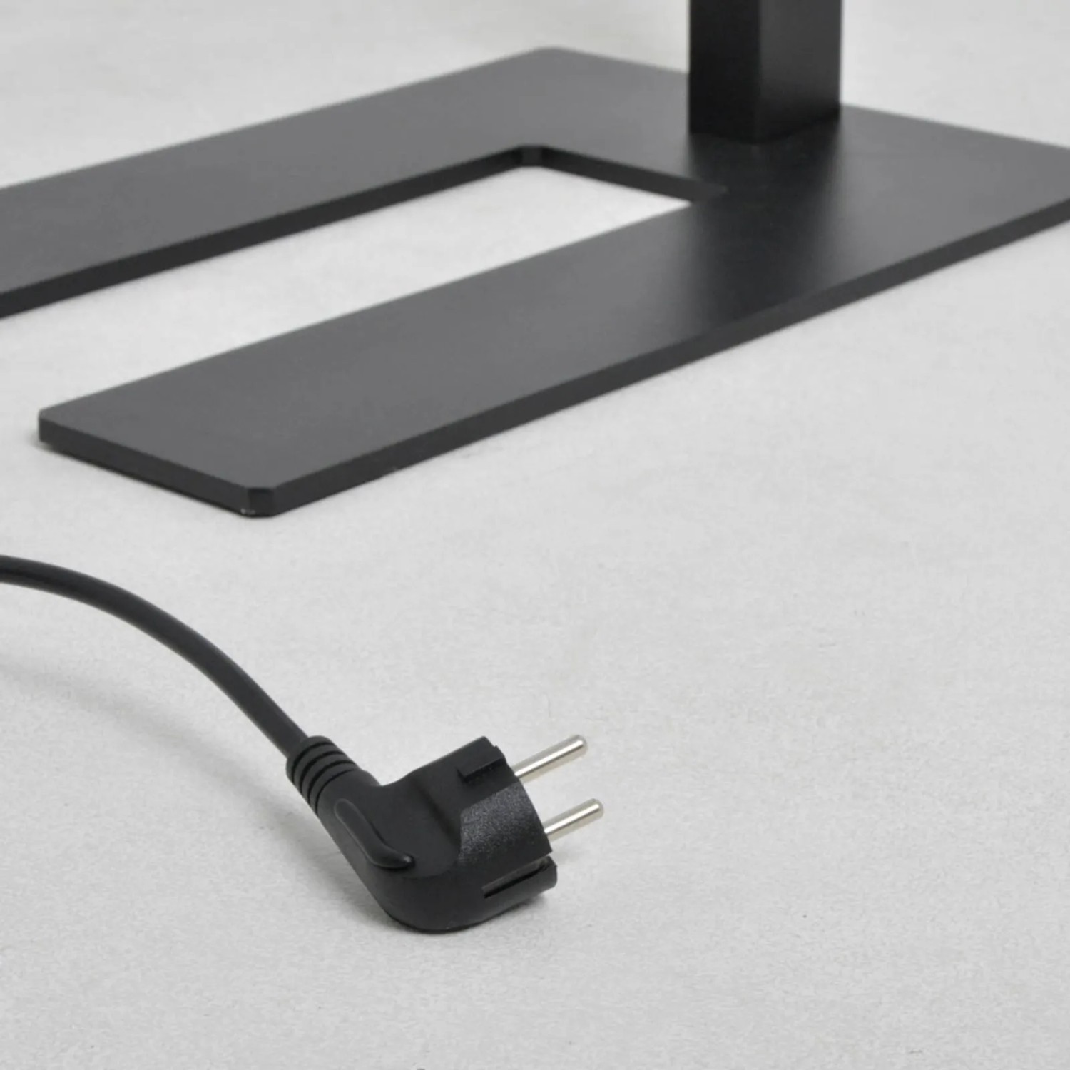 Detailaufnahme: Schwarze Arcchio LED Bürostehleuchte Logan, U-förmiger Fuß und Stecker.