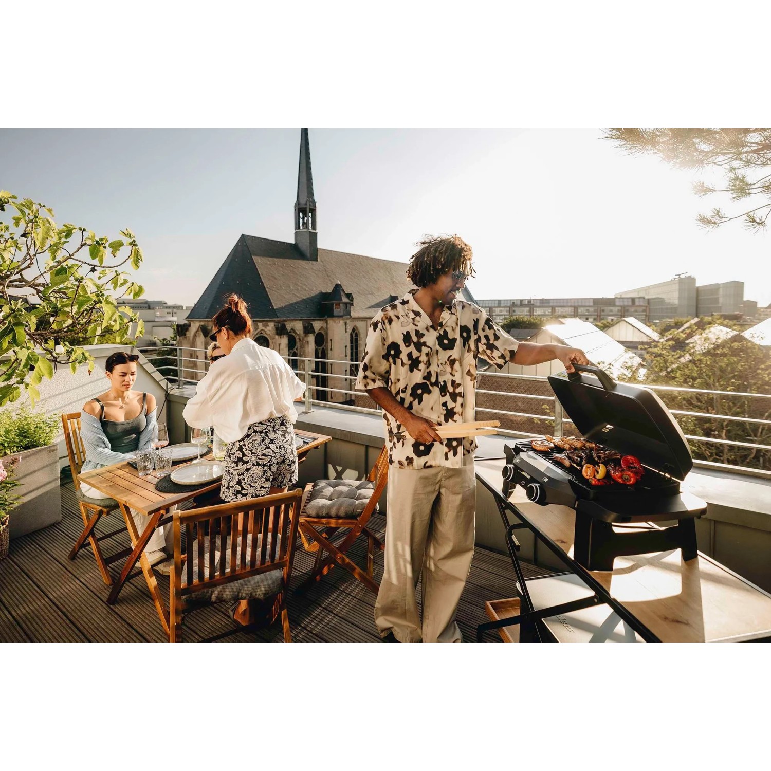 Enders Elektrogrill eUrban 2 Mobil auf Dachterrasse mit grillenden Personen.