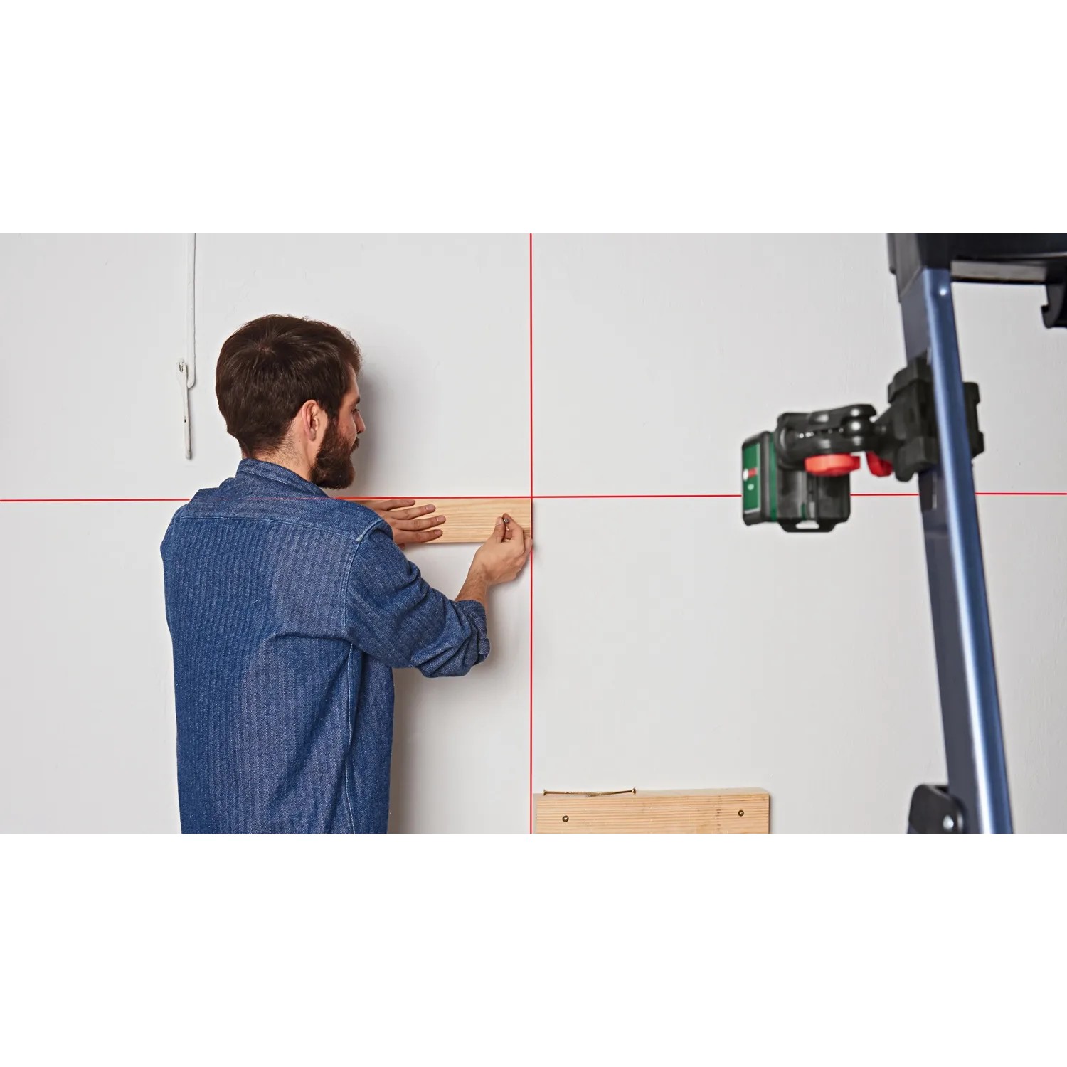 Bosch Quigo Kreuzlinienlaser mit MM 2 Universalklemme im Einsatz beim Ausrichten.