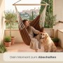 Brauner AMANKA Hängesessel aus Baumwolle, Frau entspannt mit Hund auf Balkon. Ideal als Schwebesessel, bis 150 kg belastbar.