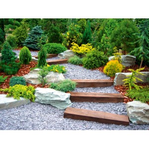 Gartenweg mit Unkrautvlies unter Kies, Holzstufen und Pflanzen.