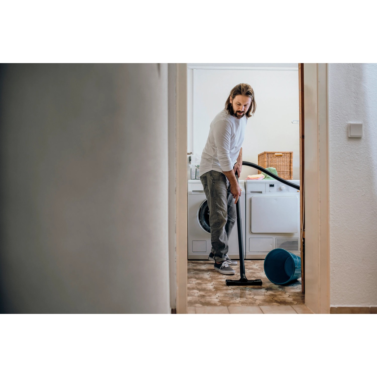 Mann saugt mit Kärcher Nass-Trockensauger WD 1 Classic Wasser in Waschküche.