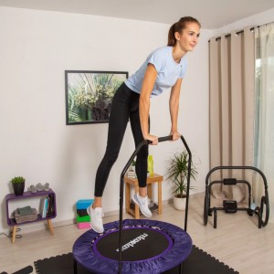 Frau trainiert auf lila faltbarem Relaxdays Trampolin mit Haltestange. Perfekt für Indoor Fitness, Balance & Koordination.