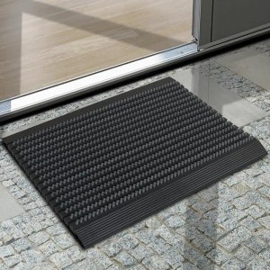 Graue Karat Fußmatte Power Brush 50x80 cm mit Bürsten vor einer Tür.