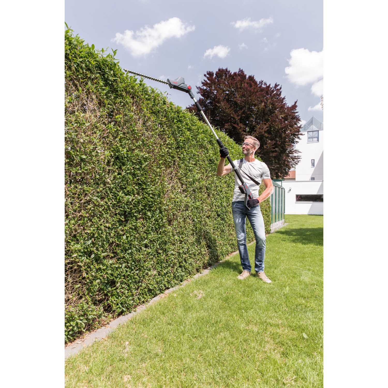 Mann schneidet Hecke mit Al-Ko Akku-Hochheckenschere HTA 1845, kompatibel mit Bosch Akku.