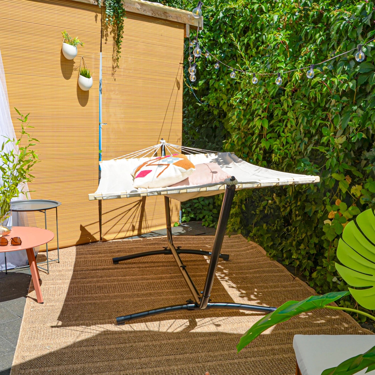 Beige AMANKA Hängematte 200x120 cm mit schwarzem Gestell (310 cm) im Garten.