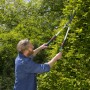 Mann schneidet Hecke mit Gardena TeleCut Teleskop-Heckenschere. Hand-Heckenschere mit ausziehbaren Griffen.
