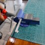 CCLIFE Schraubstock 100mm aus Gusseisen auf Werkbank mit Werkstück fixiert.