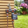Gardena Bewässerungscomputer Select am Wasserhahn mit angeschlossenen Schläuchen im Garten.