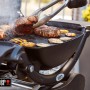 Schwarzer Weber Gasgrill Q 1200 mit Rollwagen beim Grillen von Steaks und Gemüse.