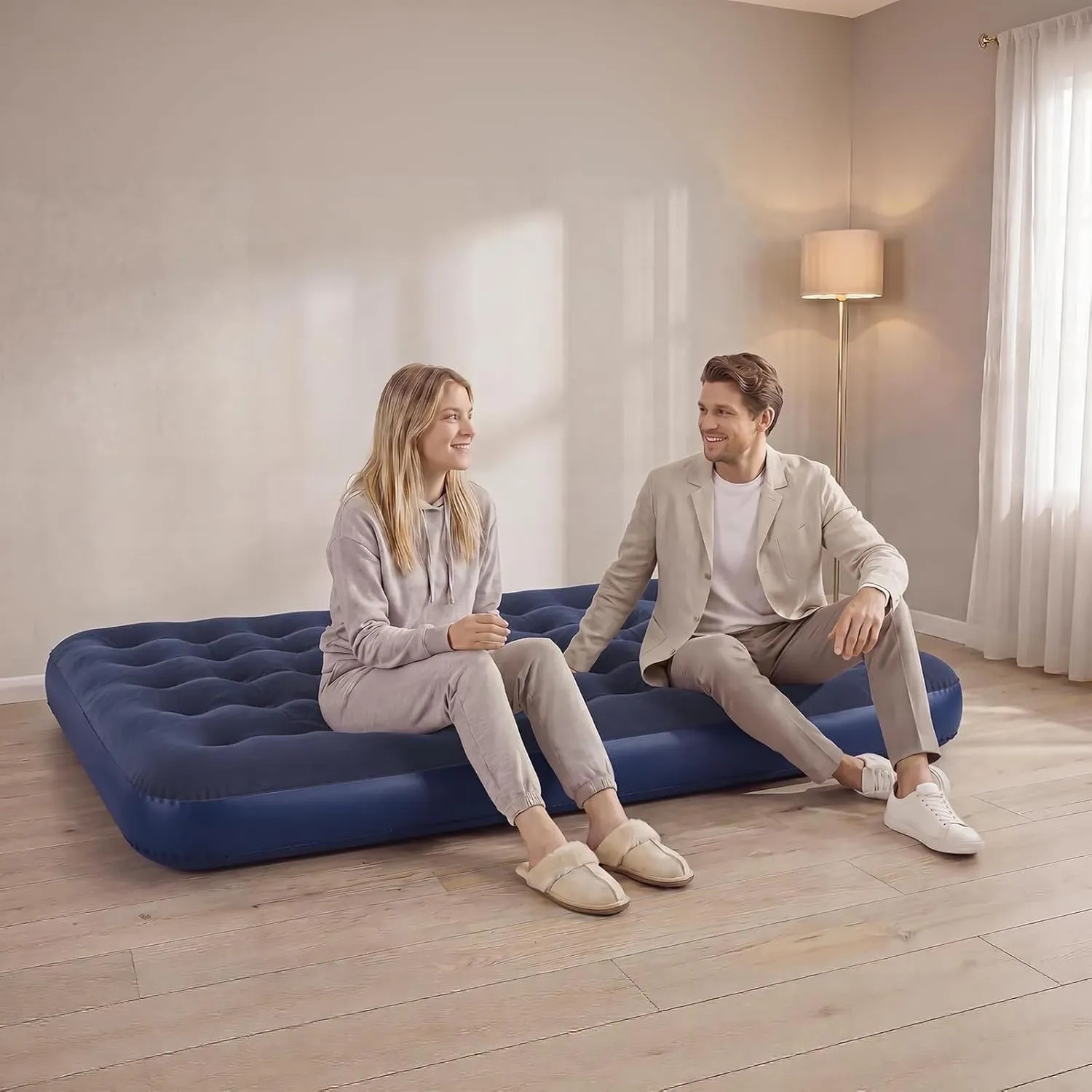 Komfortable blaue Luftmatratze für 2 Personen, auf der ein Paar in einem hellen Zimmer sitzt. Ideal für Camping & Outdoor.