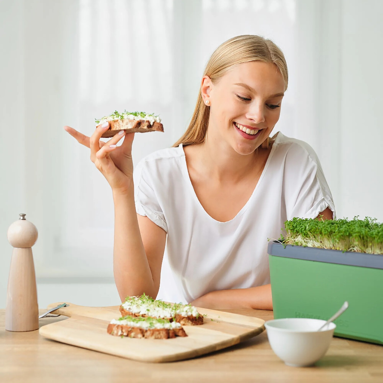 Frau isst Brot mit Kresse aus dem Gusta Garden Anzuchtsgefäß Harry Herbs.