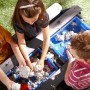 Kinder spielen am grauen Axi Sand- und Wasser-Picknicktisch Nick mit blauem Behälter.