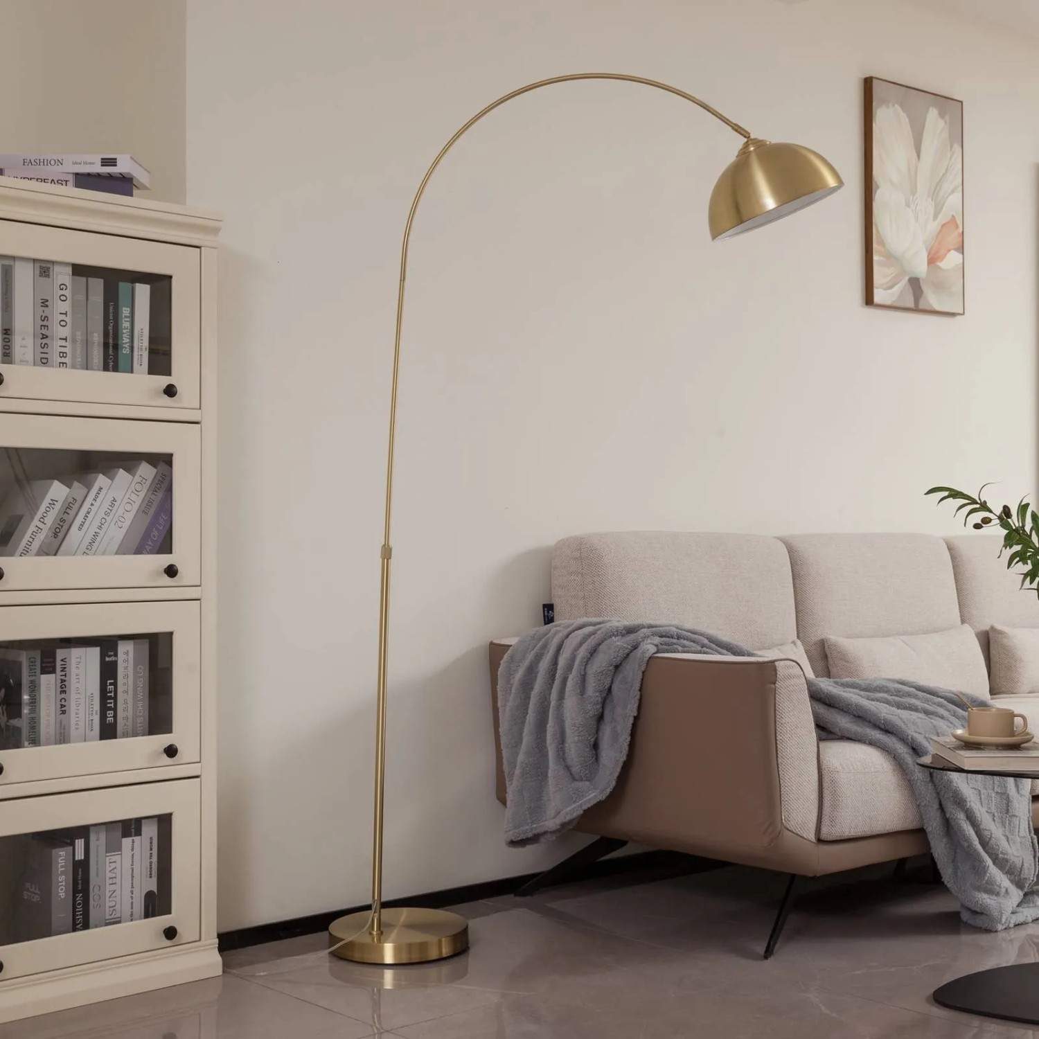 Moderne Lindby Bogenleuchte Lennart aus goldfarbenem Messing-Metall im Wohnzimmer. Elegante Stehlampe mit gewölbtem Schirm und rundem Fuß.