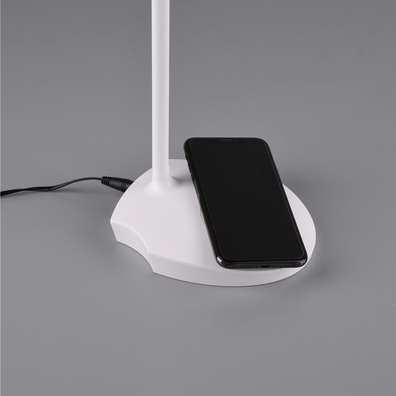 Weiße Reality LED-Touch-Tischlampe Load mit induktiver Ladestation und Smartphone.